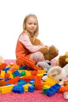 bored little girl in a mess of toys
